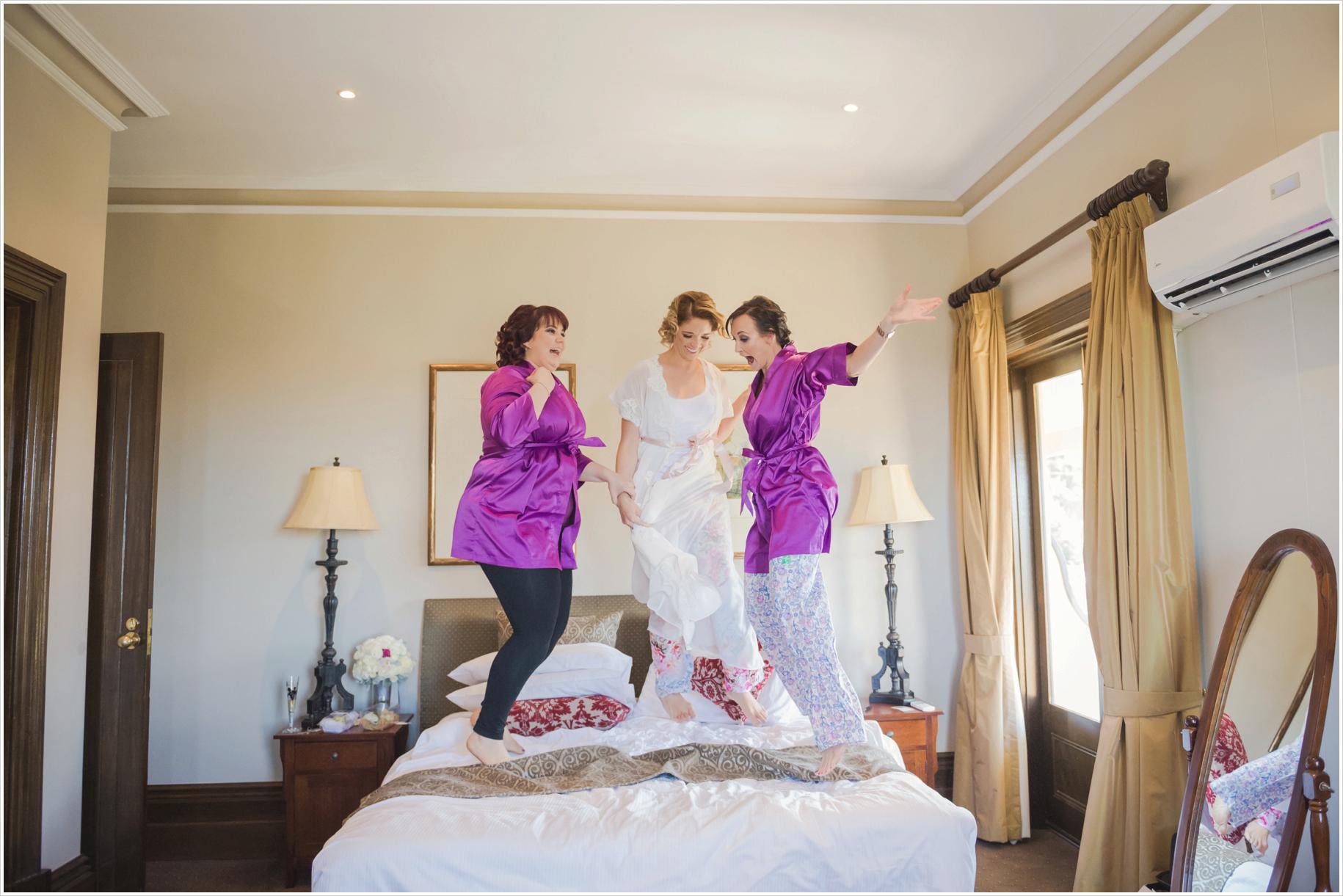 bride and bridesmaids jumping on bed